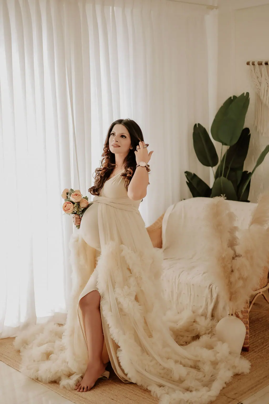 Expectant mother holding peach roses in a cream ruffled tulle gown, maternity photoshoot at WonderBump Studio, Bengaluru