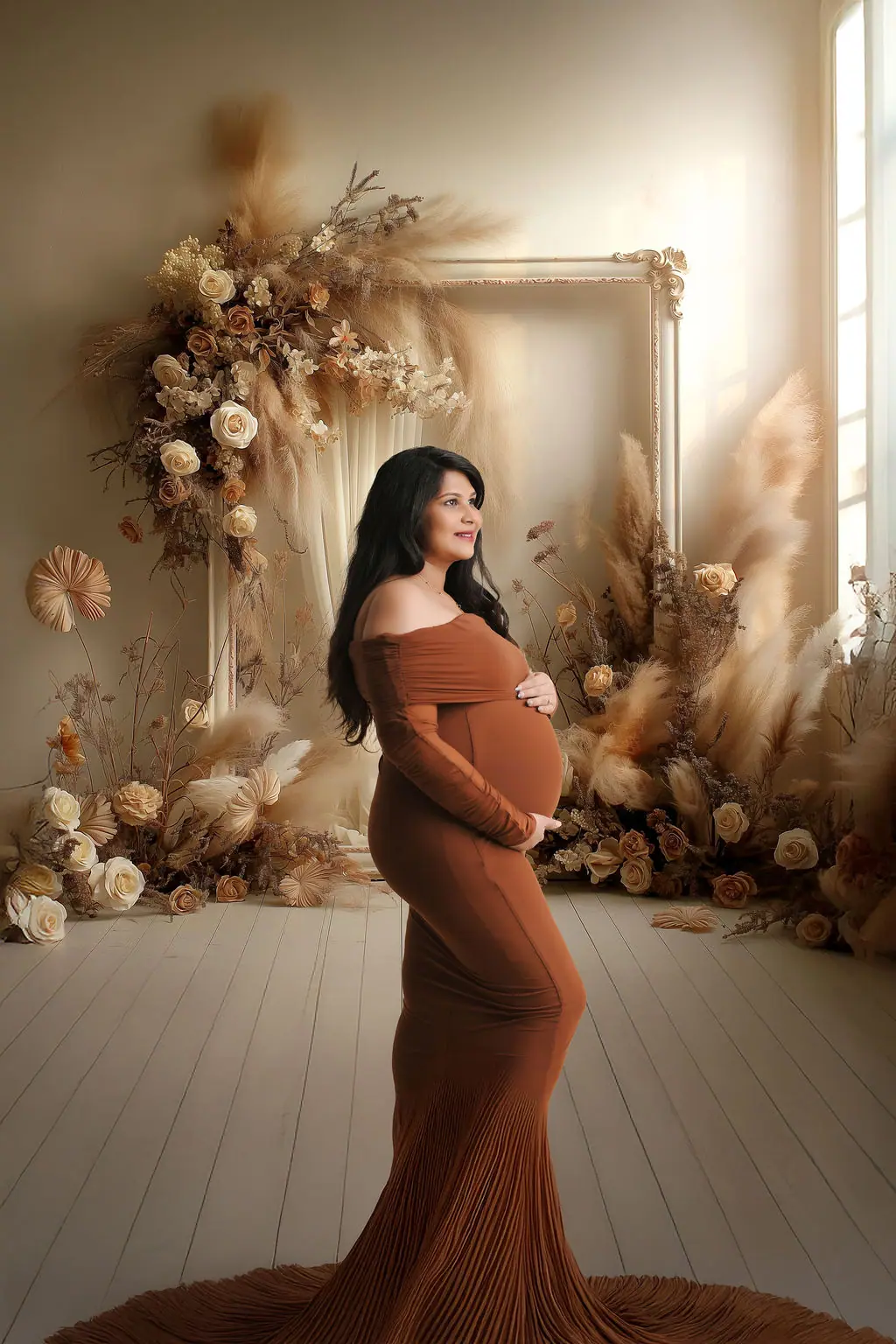 Expectant mother in a rust off-shoulder gown before a printed dried flower backdrop, maternity photoshoot at WonderBump Studio, Bengaluru