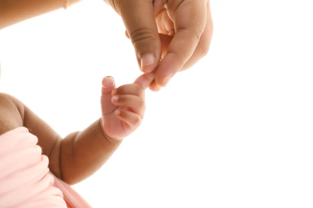 Close-up of a baby's tiny hand holding a parent's fingertip on a white backdrop, newborn photoshoot at WonderBump Studio, Bengaluru