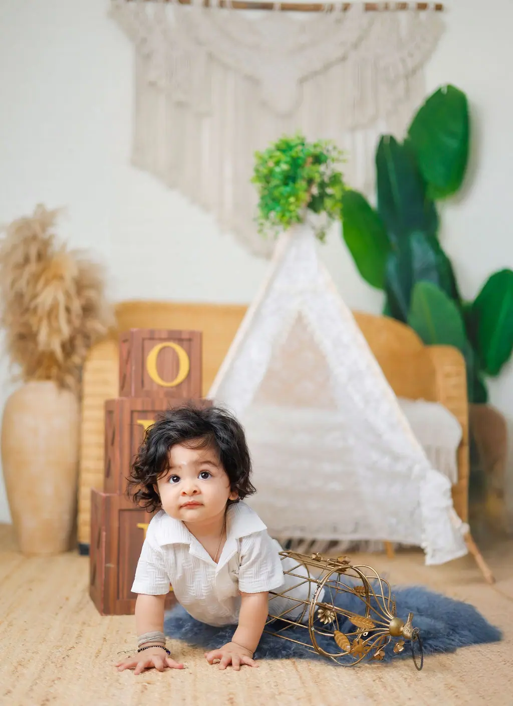 Baby crawling on a grey fur rug in a white shirt beside a lace teepee and ONE blocks, toddler photoshoot at WonderBump Studio, Bengaluru