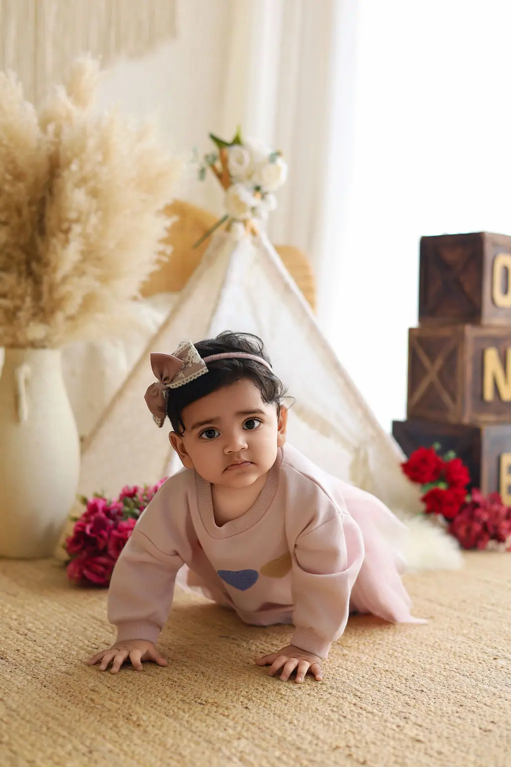 Baby crawling in a pink heart sweatshirt and tutu by a lace teepee and ONE blocks, toddler photoshoot at WonderBump Studio, Bengaluru